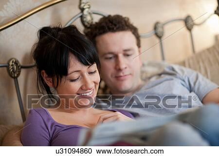 Couple reading newspaper in bed View Large Photo Image Stock Image - Couple reading newspaper in bed. Fotosearch