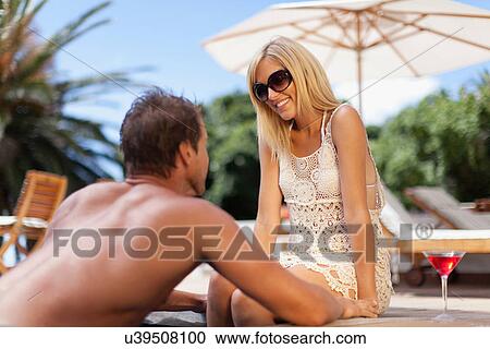 Stock Image - Couple relaxing by swimming pool. Fotosearch
