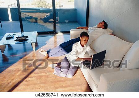 Couple relaxing together in living room View Large Photo Image Stock Image - Couple relaxing together in living room. Fotosearch