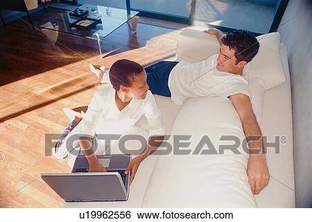 Stock Photograph - Couple relaxing together in living room. Fotosearch