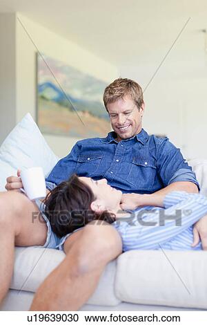 Couple relaxing together on couch View Large Photo Image Stock Image - Couple relaxing together on couch. Fotosearch