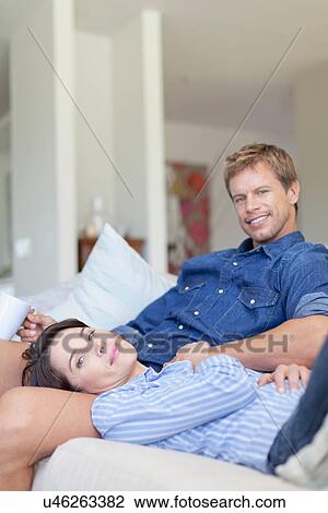 Couple relaxing together on couch View Large Photo Image Stock Image - Couple relaxing together on couch. Fotosearch