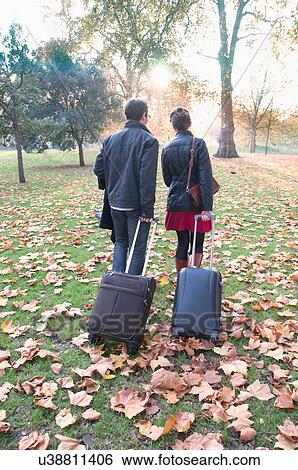 Couple rolling luggage in park View Large Photo Image Stock Photograph - Couple rolling luggage in park. Fotosearch