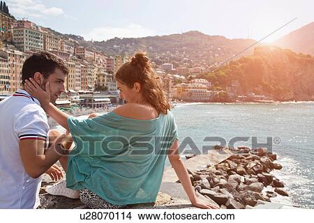 Couple sitting on stone wall by ocean View Large Photo Image Picture - Couple sitting on stone wall by ocean. Fotosearch