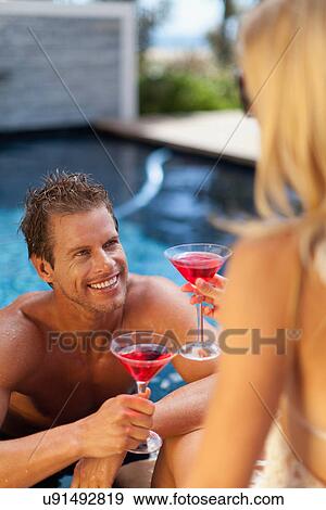 Couple toasting each other in pool View Large Photo Image Stock Photo - Couple toasting each other in pool. Fotosearch