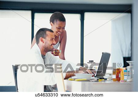 Couple using laptop at breakfast table View Large Photo Image Stock Image - Couple using laptop at breakfast table. Fotosearch
