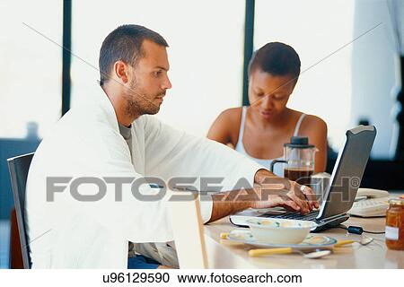 Couple using laptop at breakfast table View Large Photo Image Stock Image - Couple using laptop at breakfast table. Fotosearch