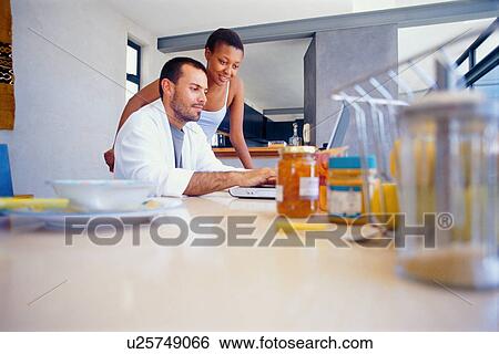 Stock Photograph - Couple using laptop at breakfast table. Fotosearch