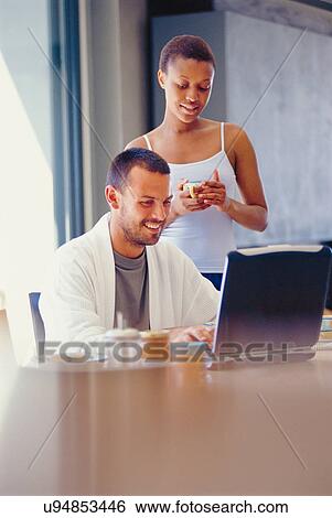 Couple using laptop at breakfast table View Large Photo Image Stock Photograph - Couple using laptop at breakfast table. Fotosearch