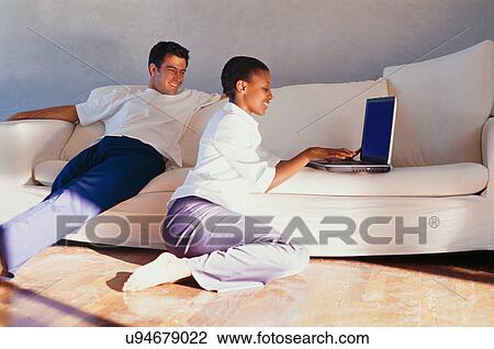 Couple using laptop together on couch View Large Photo Image Stock Image - Couple using laptop together on couch. Fotosearch