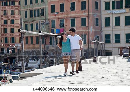 Stock Photograph - Couple walking along urban pier. Fotosearch