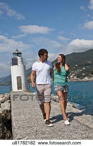 Stock Image - Couple walking by lighthouse. Fotosearch