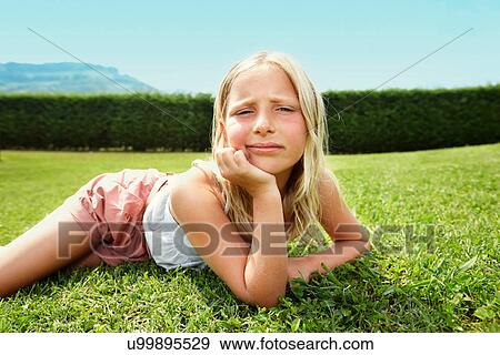 Stock Photo - Curious girl laying in grass. Fotosearch