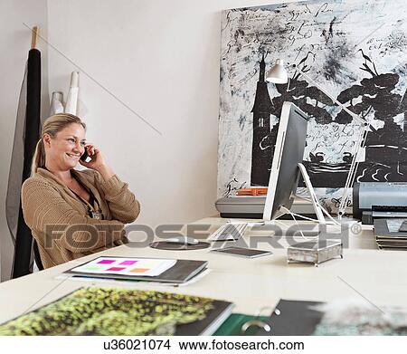 Picture - Designer on cell phone at computer. Fotosearch