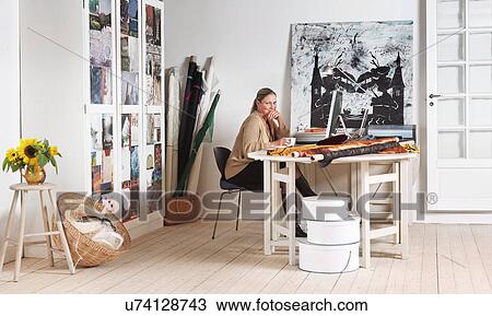 Stock Image - Designer sitting at computer in office. Fotosearch