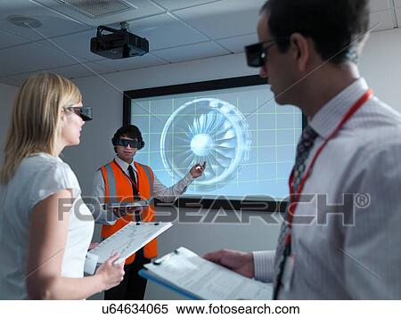 Stock Photography - Engineers and apprentice in 3D glasses with clipboards in front of engine on 3D screen. Fotosearch