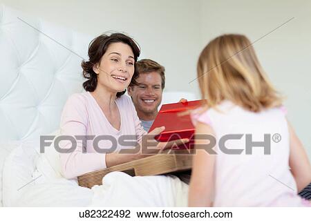 Stock Image - Family bringing mother presents in bed. Fotosearch
