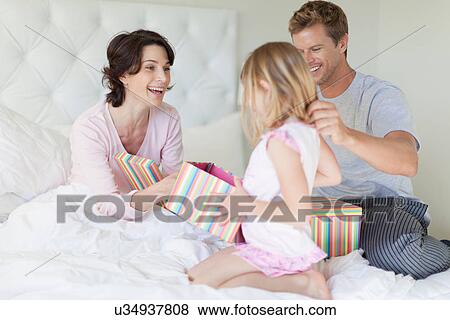 Family bringing mother presents in bed View Large Photo Image Stock Photo - Family bringing mother presents in bed. Fotosearch