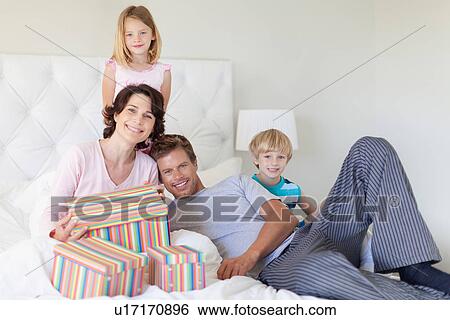 Family bringing mother presents in bed View Large Photo Image Stock Photograph - Family bringing mother presents in bed. Fotosearch