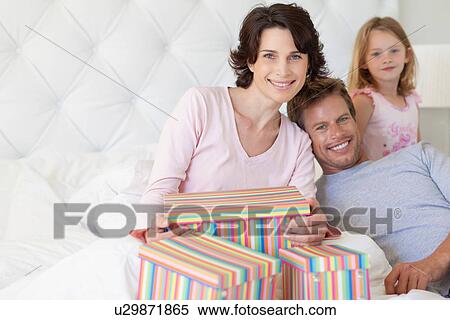Stock Photography - Family bringing mother presents in bed. Fotosearch