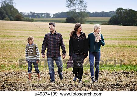 Family walking together in grassy field View Large Photo Image Stock Photo - Family walking together in grassy field. Fotosearch