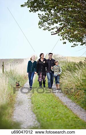 Stock Image - Family walking together on rural road. Fotosearch
