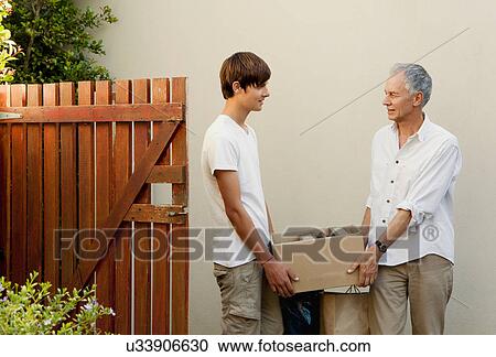 Stock Image - Father and son carrying box together. Fotosearch