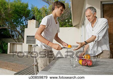 Stock Photo - Father and son clearing table outdoors. Fotosearch