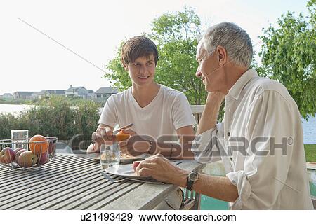 Stock Photo - Father and son eating fruit outdoors. Fotosearch