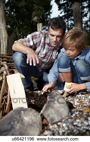 Stock Photograph - Father and son lighting fire outdoors. Fotosearch
