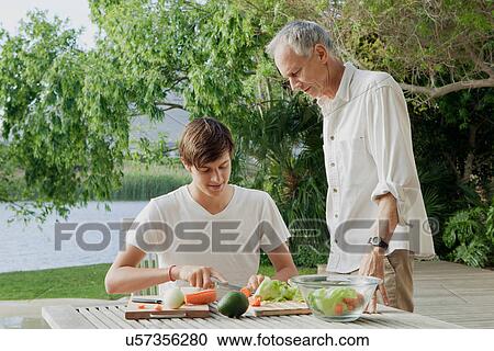 Stock Image - Father and son making salad outdoors. Fotosearch