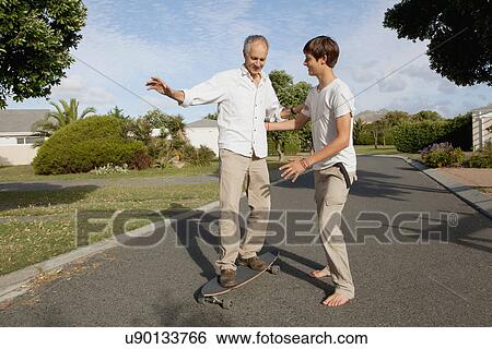 Father and son playing with skateboard View Large Photo Image Stock Photograph - Father and son playing with skateboard. Fotosearch