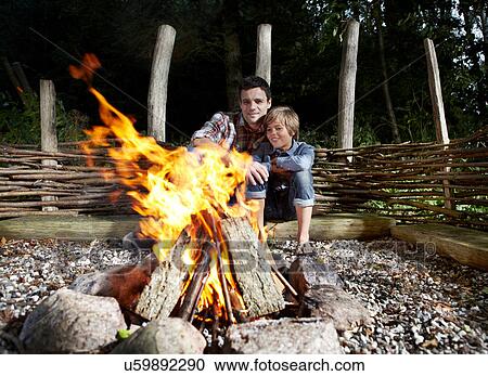 Father and son sitting by fire outdoors View Large Photo Image Stock Image - Father and son sitting by fire outdoors. Fotosearch