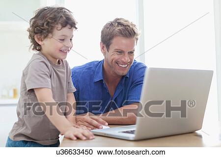 Stock Image - Father and son using laptop together. Fotosearch