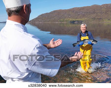 Fisherman in loch giving freshly caught salmon to chef View Large Photo Image Stock Image - Fisherman in loch giving freshly caught salmon to chef. Fotosearch