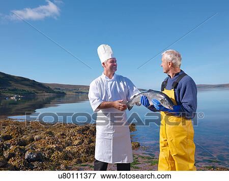 Fisherman in loch giving freshly caught salmon to chef View Large Photo Image Stock Photo - Fisherman in loch giving freshly caught salmon to chef. Fotosearch