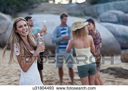 Stock Image - Friends drinking and relaxing on beach. Fotosearch
