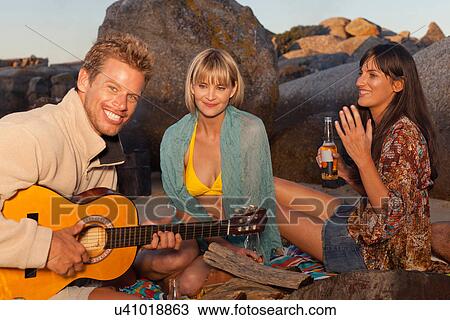 Stock Image - Friends drinking and relaxing on beach. Fotosearch