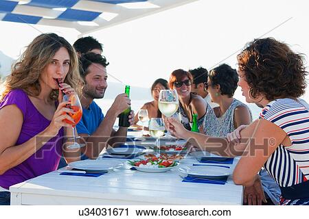 Friends drinking at table outdoors View Large Photo Image Stock Image - Friends drinking at table outdoors. Fotosearch
