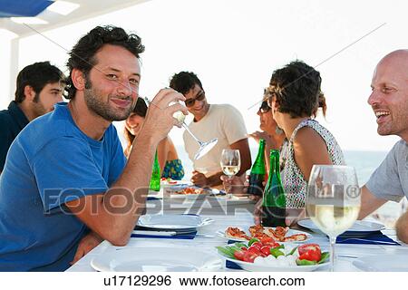 Stock Photograph - Friends drinking at table outdoors. Fotosearch