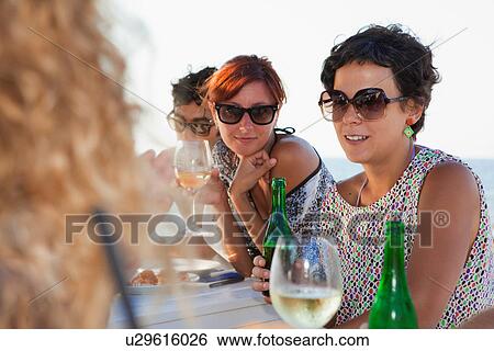 Friends drinking at table outdoors View Large Photo Image Stock Photograph - Friends drinking at table outdoors. Fotosearch