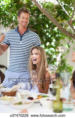 Stock Photo - Friends eating at table outdoors. Fotosearch
