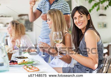 Stock Photography - Friends eating at table outdoors. Fotosearch