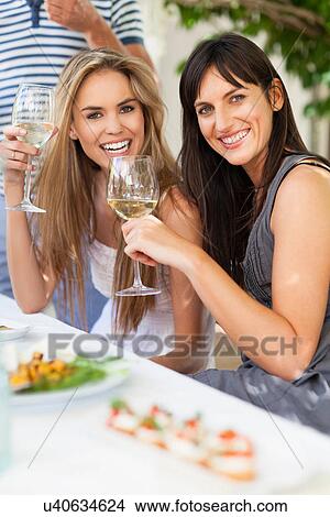 Picture - Friends having wine at table outdoors. Fotosearch