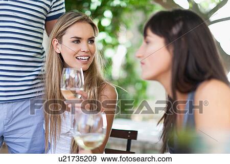 Friends having wine at table outdoors View Large Photo Image Stock Photo - Friends having wine at table outdoors. Fotosearch
