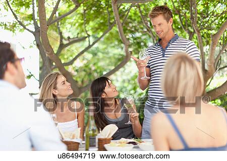 Friends having wine at table outdoors View Large Photo Image Stock Photo - Friends having wine at table outdoors. Fotosearch