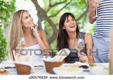 Friends having wine at table outdoors View Large Photo Image Stock Photo - Friends having wine at table outdoors. Fotosearch