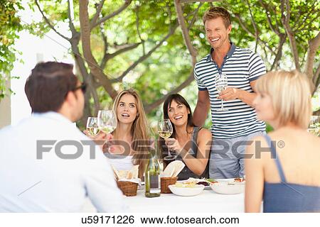 Friends having wine at table outdoors View Large Photo Image Stock Photograph - Friends having wine at table outdoors. Fotosearch