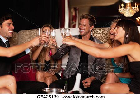 Friends toasting each other in club View Large Photo Image Stock Photo - Friends toasting each other in club. Fotosearch