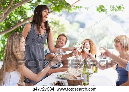 Picture - Friends toasting each other outdoors. Fotosearch